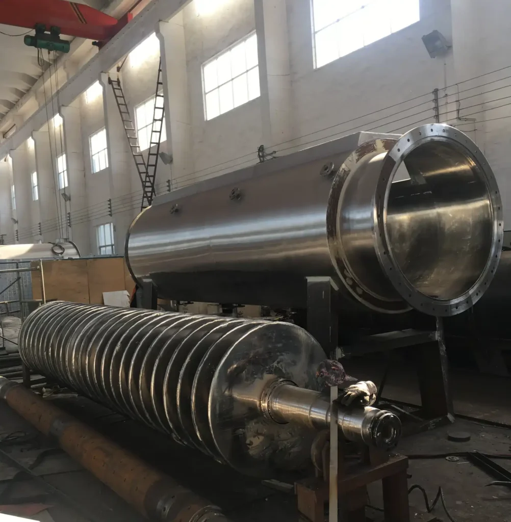 Большая дисковая сушилка промышленного назначения с цилиндрическим корпусом из нержавеющей стали и спиральным дисковым валом, готовая к монтажу или техническому обслуживанию.