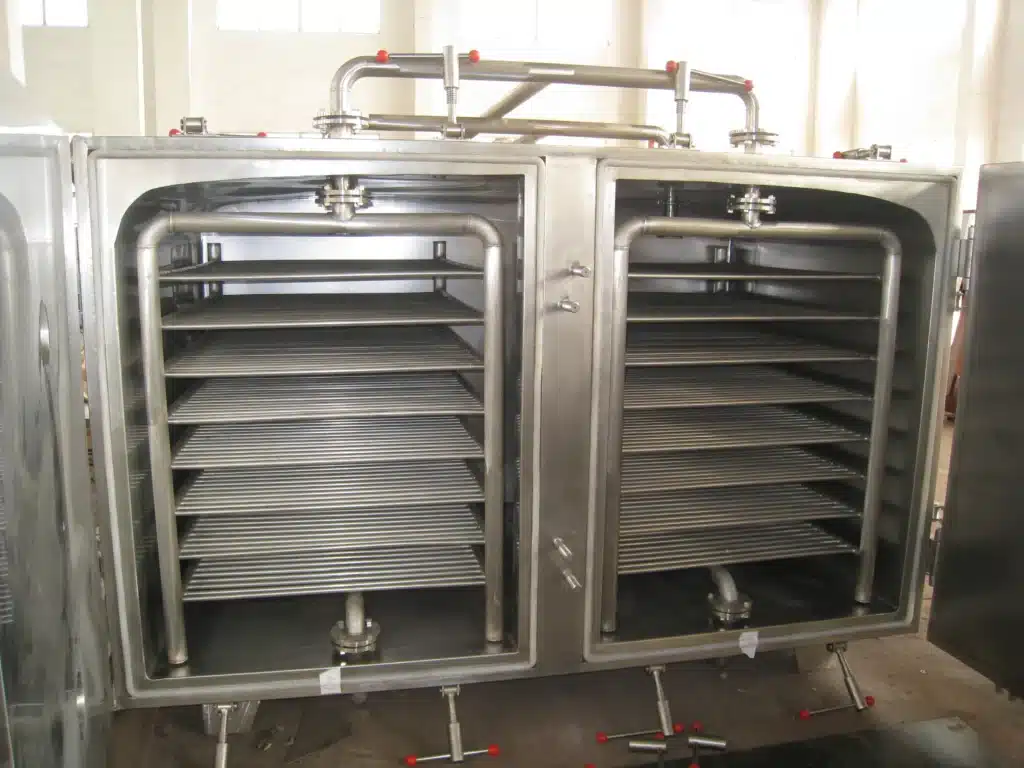 Статическая вакуумная сушилка с прямоугольным корпусом из нержавеющей стали, несколькими круглыми манометрами и портами на передней панели, установленная на прочных ножках с роликами.