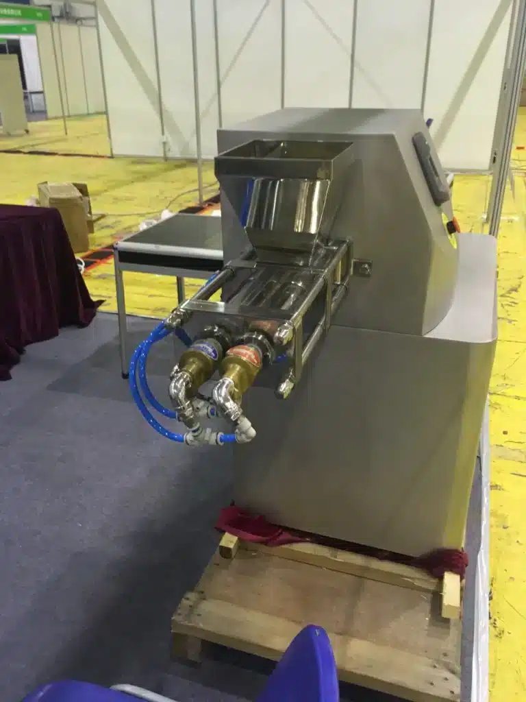 Screw Extruder untuk granulasi, yang menampilkan hopper, bodi baja tahan karat, dan mekanisme sekrup yang rumit, dipamerkan di pameran industri.