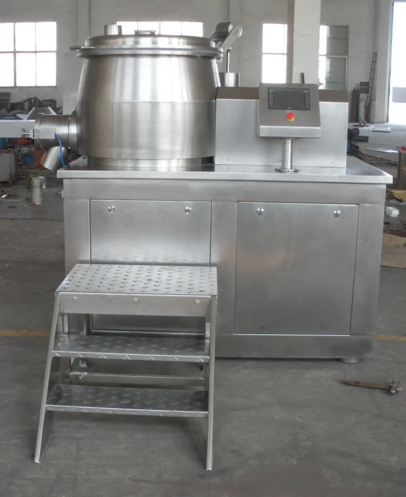 Granulator Pencampur Cepat Basah yang menampilkan mangkuk pencampur besar dengan tutup bening, konstruksi baja tahan karat, dan berbagai pipa saluran masuk, yang diletakkan di ruang produksi industri dengan cahaya alami.