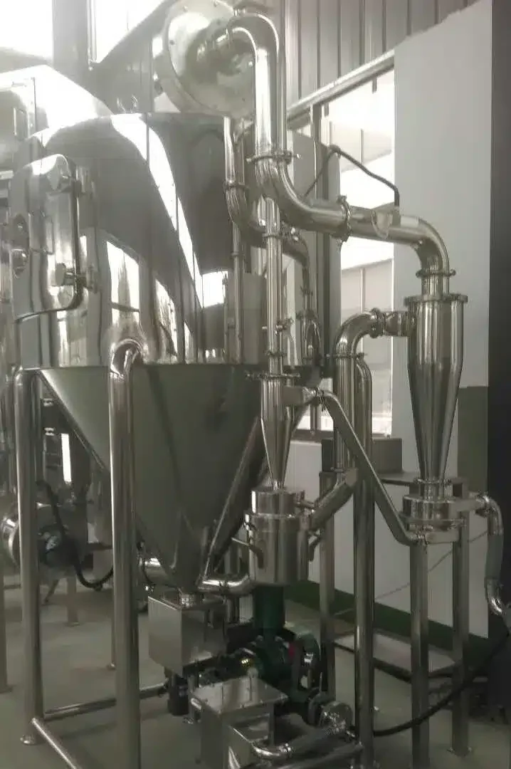 Ein industrieller Extrakt-Sprühtrockner in einem Reinraum mit einer Edelstahlkonstruktion mit komplizierten Rohrleitungen und einem konischen Auffangtrichter. Sensoren und Regelventile sind sichtbar, was auf einen präzisen und kontrollierten Trocknungsprozess für Extrakte hindeutet.