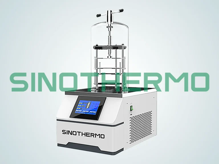 A benchtop freeze dryer by SINOTHERMO with a digital touchscreen interface, transparent drying chamber, and shelf system, set against a gradient grey background.
