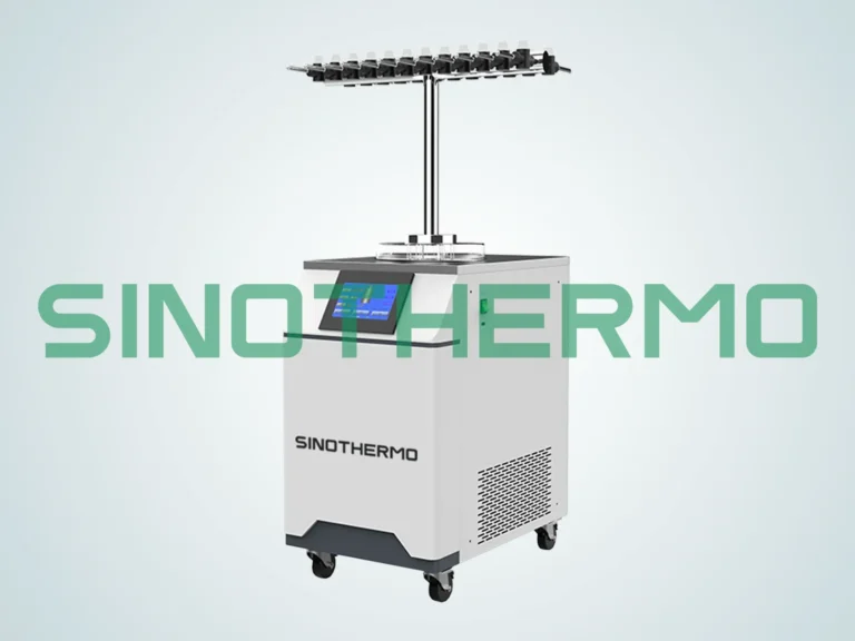 A benchtop freeze dryer with digital display, mounted on wheels, against a plain grey background, featuring a logo "SINOTHERMO" on its side.